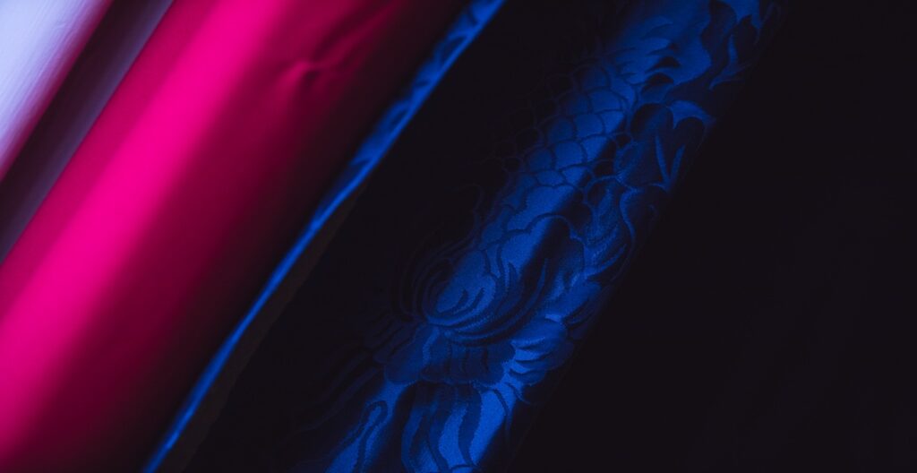 Rich blue silk fabric close up with a plain red silk next to it