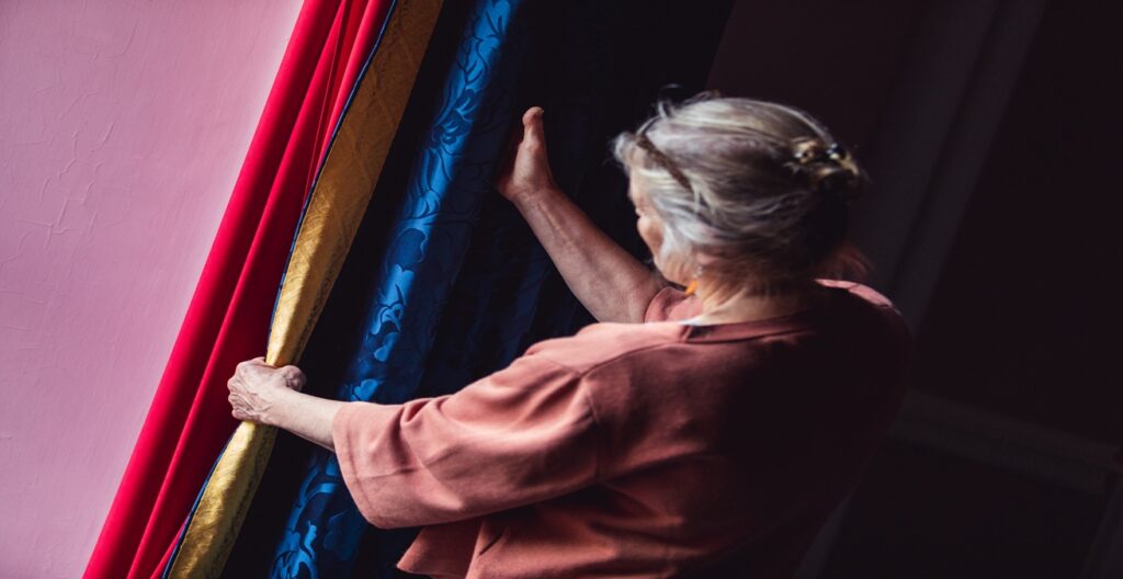 A lady holding the Auckland Castle curtains, a combination of rich blue, gold and red silk fabrics sewn together