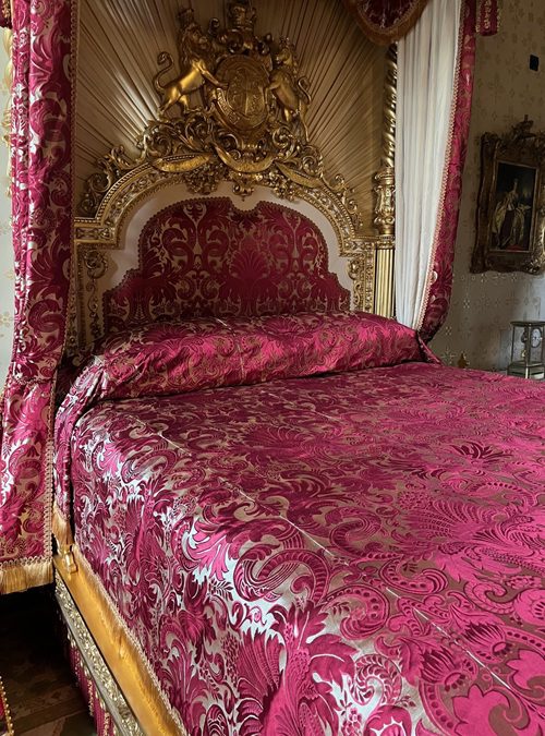Guilded bed showing headboard and coverlet in crimson and white silk