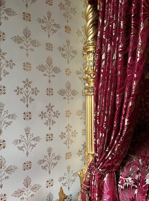 Gold leaf wall stencil with crimson and white silk bed curtain
