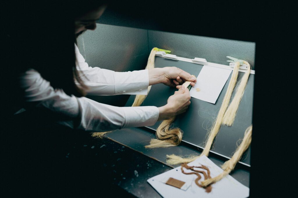 Woman comparing gold yarn sample of custom colour to standard colour in lightbox