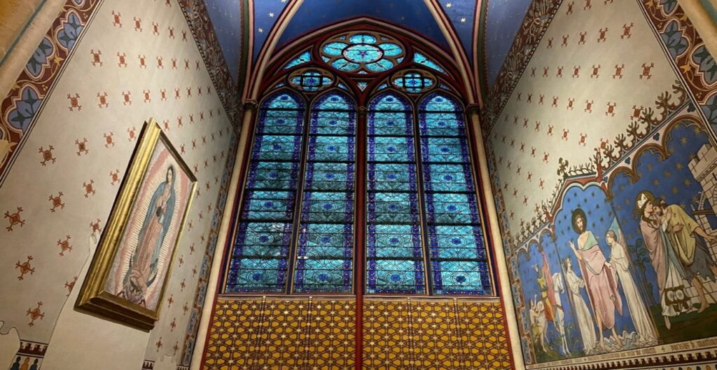 Norte Dame gothic window with blue stained glass and decorative painted blue ceiling with gold stars