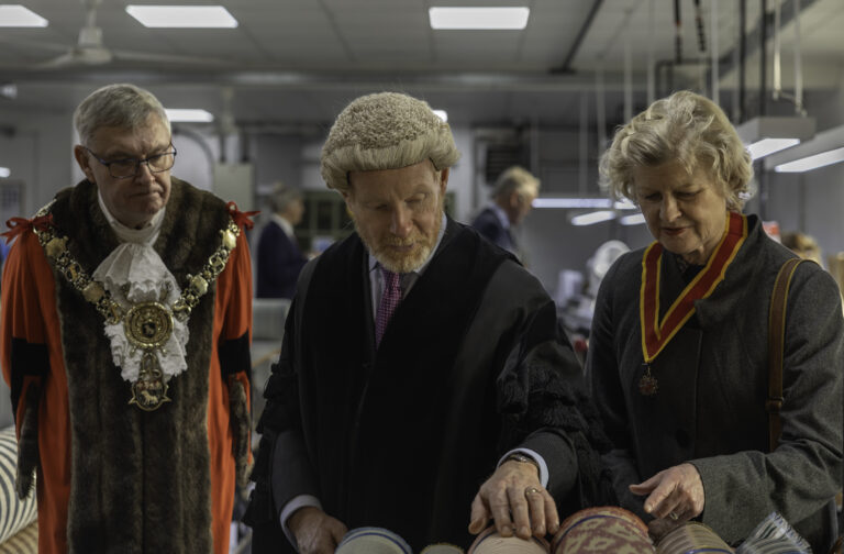 Deputy Lieutenants and representatives of Sudbury admiring fabric rolls in inspection room