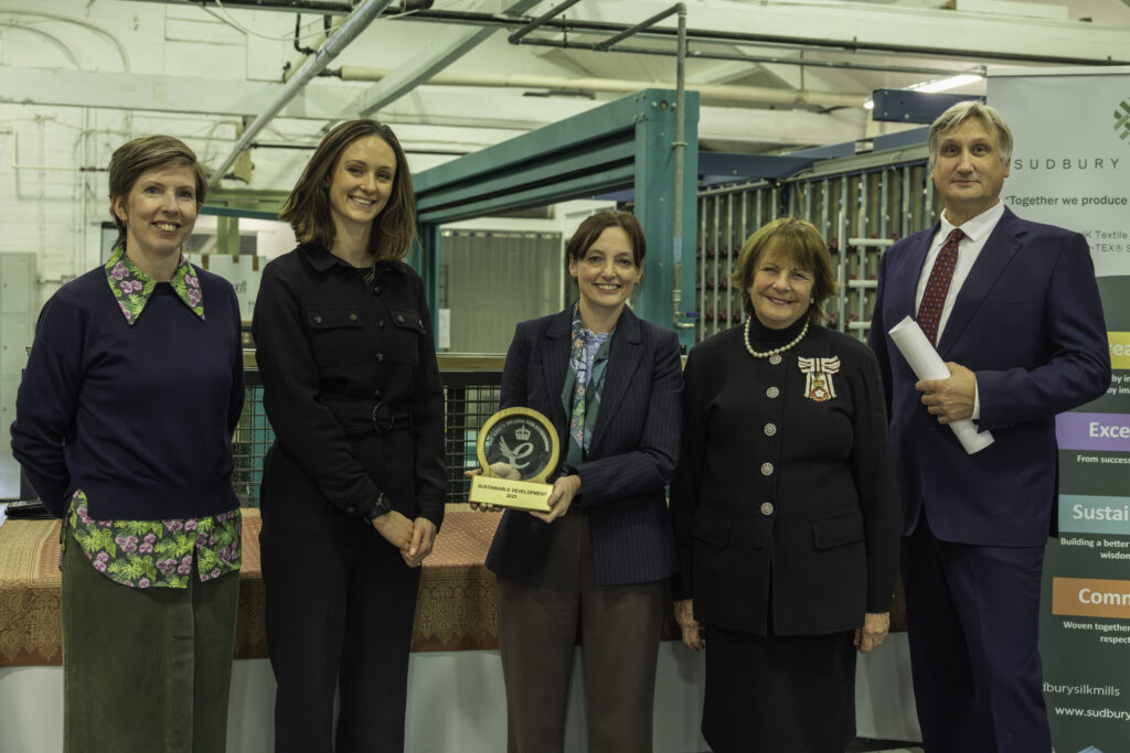 Members of Humphries Weaving and Sudbury Silk Mills posing with Lady Clare whilst holding scroll and trophy for King's Award