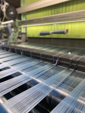 Two tones of blue warp yarns the back of a loom