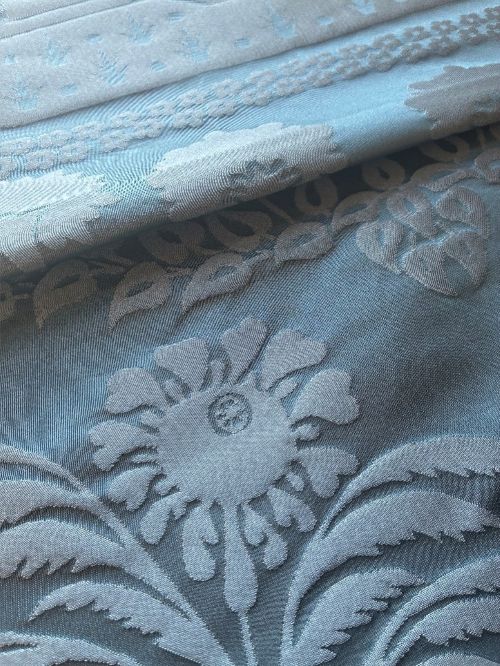 Close up of pale blue jacquard fabric with raised floral and leaf motifs